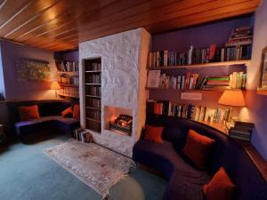 een woonkamer met een open haard en boekenplanken bij The Four Seasons Hotel in Saint Fillans