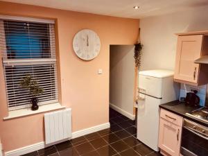 uma cozinha com um relógio na parede e um frigorífico em 'Afton' at stayBOOM em Lancaster