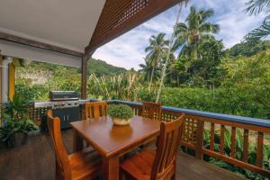 een houten tafel en stoelen op een terras met uitzicht bij Cook Islands Holiday Villas - Turtle Villa in Arorangi