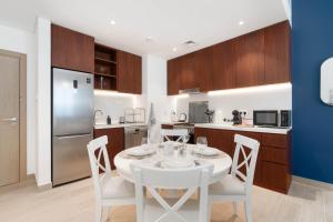 a kitchen with a white table and white chairs at Ultimate Stay for 4 with Sunset Balcony at La Mer in Dubai +48 photos