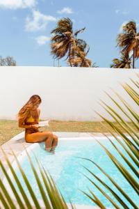 a woman in a bikini sitting on the edge of a swimming pool at Pousada Naná in Prea