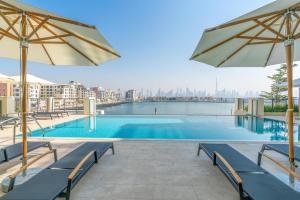 a swimming pool with umbrellas and a view of the city at Ultimate Stay / 4 People / Beachfront / Sea View / Balcony Sunset / Brand New / La Mer in Dubai