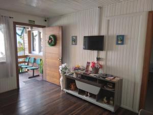 sala de estar con mesa y TV en la pared en Pousada Genial, en Gramado