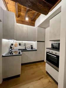 a kitchen with white cabinets and a stove and sink at La dimora della Giudecca - 13 in Cuneo