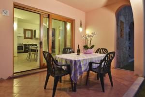 una sala da pranzo con tavolo, sedie e una bottiglia di vino di Residence Le Zagare a San Teodoro