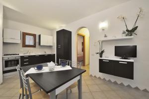 a kitchen with a table with chairs and a television at Residence Le Zagare in San Teodoro
