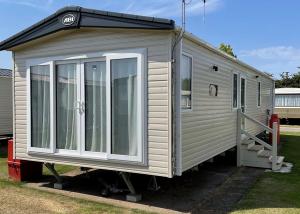 a small white tiny house with a porch at Willows Holiday Park in Withernsea