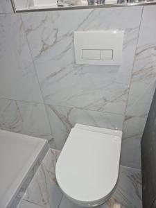 aseo blanco en un baño con paredes de mármol en Oberursel, en Eichwäldchen