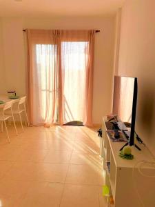 uma sala de estar com uma grande janela e uma televisão em Apartament Maia Ocean em Corralejo