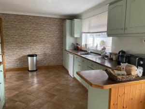 kuchnia z zielonymi szafkami i podłogą wyłożoną kafelkami w obiekcie Ash rock House w mieście Haverfordwest