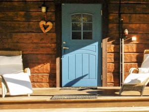 Holiday home MORA III في Börka: باب أزرق على منزل خشبي مع كرسيين