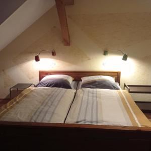 een bed op zolder met twee lampjes erop bij Botanische Botschaft in Strodehne