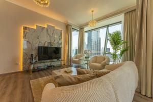 WORLD CLASS 3BR with full BURJ KHALIFA and FOUNTAIN VIEW في دبي: غرفة معيشة بها أريكة وتلفزيون