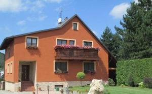 a orange house with a balcony with flowers on it at Apartmány Okoun in Velké Losiny