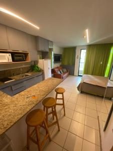 uma cozinha e sala de estar com uma cama e bancos em Studio Muro Alto em Porto de Galinhas