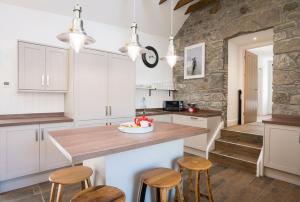 a kitchen with white cabinets and wooden stools at Dairy Cottage in Gatehouse of Fleet