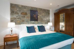 a bedroom with a large bed and a stone wall at Dairy Cottage in Gatehouse of Fleet