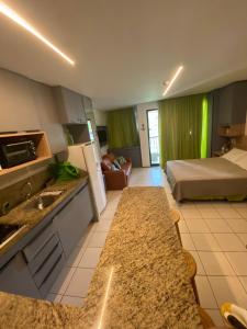 a kitchen and a bedroom with a bed and a kitchen counter at Studio Muro Alto in Porto De Galinhas