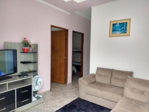 a living room with a couch and a television at Casa de temporada in São João Batista do Glória