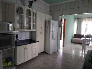 uma cozinha com armários brancos e um frigorífico branco em Casa de temporada em São João Batista do Glória