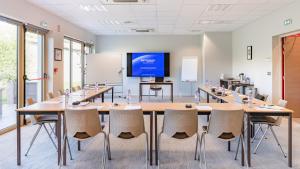 uma sala de conferências com uma grande mesa e cadeiras em Best Western Hôtel des Barolles - Lyon Sud em Brignais