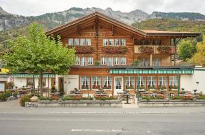 a wooden building with tables and chairs in front of it at Hotel Steinbock in Brienz