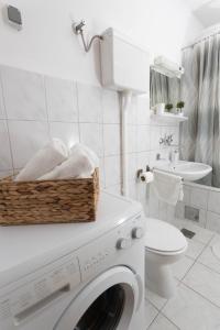 a white bathroom with a washing machine and a toilet at Apartman Tihana in Vinkovci