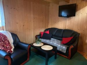 a living room with a black leather couch and a table at Jaśminowa Przystań in Stegna