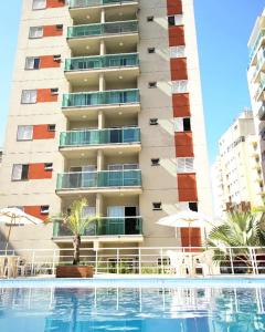 a hotel with a swimming pool in front of a building at Apes Enseada Guarujá in Guarujá