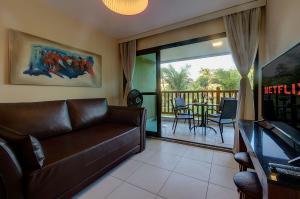 Condomínio no melhor da Praia de Cumbuco por Carpediem في كومبوكو: غرفة معيشة مع أريكة جلدية وشرفة