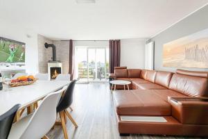 a living room with a brown leather couch and a kitchen at holiday home, Ustronie Morskie in Ustronie Morskie