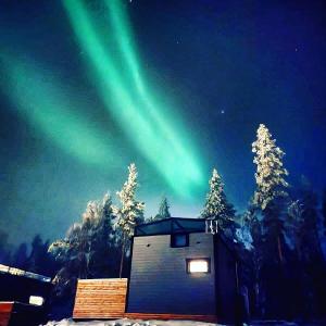 an image of the aurora borealis over a cabin at Levi Sky Igloo with private sauna and hot tub in Levi