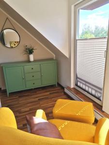 a living room with yellow furniture and a green dresser at Fewo "Am Bienenstock" in Dallgow-Döberitz in Dallgow