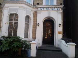 un edificio blanco con una puerta con un cartel. en Chelsea House Hotel - B&B, en Londres