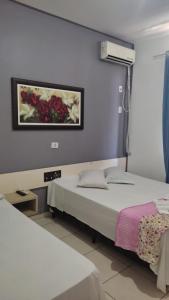 um quarto com duas camas e um quadro na parede em Hotel Foz Brasil em Foz do Iguaçu