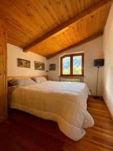 une chambre avec un grand lit avec un plafond en bois dans l'établissement Accogliente chalet in mansarda, à Courmayeur