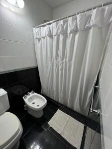 een zwart-witte badkamer met een toilet en een douche bij Departamento de Huéspedes in San Martín