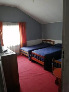 1 dormitorio con 2 camas, ventana y alfombra roja en Hostal Papo en Osorno