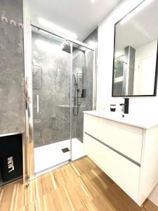 uma casa de banho com um chuveiro, um lavatório e um espelho. em Apartamento nuevo en playa Sanxenxo, con garaje em Sanxenxo