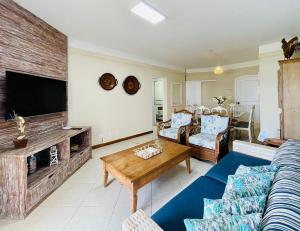 a living room with a couch and a tv at Apto c/ piscina e vista para o mar - Caraguatatuba in Caraguatatuba