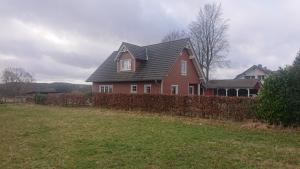 una casa roja con una valla en un campo en Privatzimmer im Schwedenhaus Unsere Kleine Farm, en Monschau