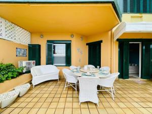 a patio with white chairs and a table on a patio at Apto c/ piscina e vista para o mar - Caraguatatuba in Caraguatatuba