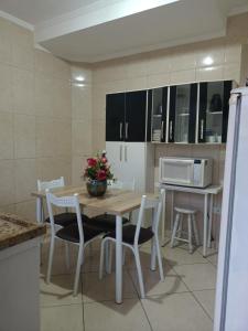 a kitchen with a table and chairs and a microwave at Lindo Sobrado in Mongaguá