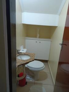 a bathroom with a white toilet and a sink at Lindo Sobrado in Mongaguá