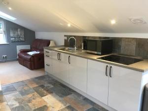 a kitchen with white cabinets and a living room at Ravens Rest in Llanwrda