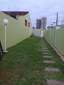 a walkway next to a green wall with grass at Lindo Sobrado in Mongaguá