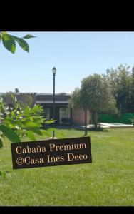 ein Schild auf einem Feld mit einem Gebäude im Hintergrund in der Unterkunft cabañas La Amelia Premium con piscina privada 2 personas in Mina Clavero