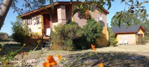 ein altes Haus mit Blumen davor in der Unterkunft cabañas La Amelia Premium con piscina privada 2 personas in Mina Clavero
