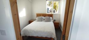 1 dormitorio con 1 cama con sábanas blancas y ventana en The Bothy en Belmont
