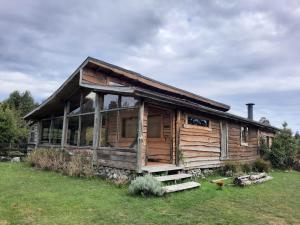 una vieja casa de madera en un campo de hierba en Cabañas Lickanantay, en Puerto Varas